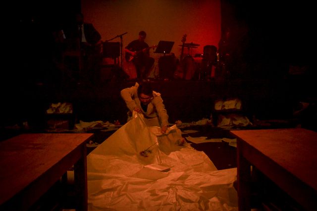 Dim red light
as Mrs Rochester (Rada) crawls along the floor
leaving a destruction of books and paper.
The band is dimly visible behind her.
