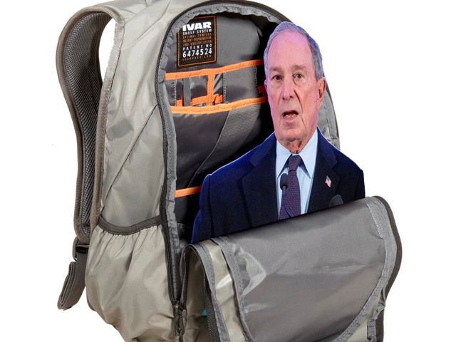 A tan backpack, half open,
revealing a cutout of Michael Bloomberg
