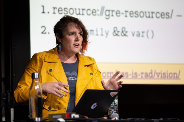 On stage behind a laptop at Smashing Conf, wearing a yellow leather jacket and headset